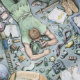 Student artwork of boy lying on the floor with scattered objects all around